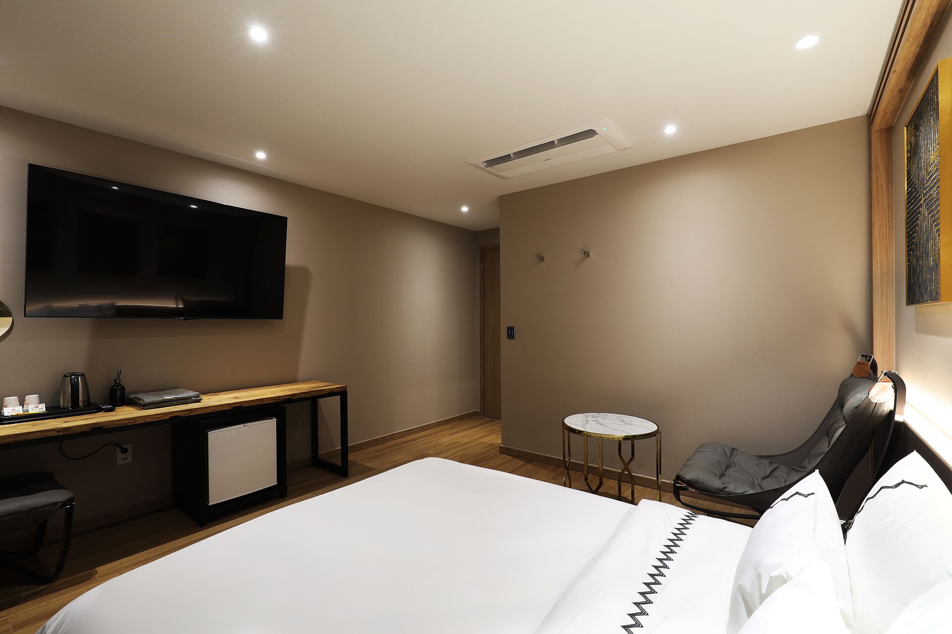 Ein Hotelzimmer mit Bett, Schreibtisch, Stuhl, Fernseher und einem kleinen Tisch.