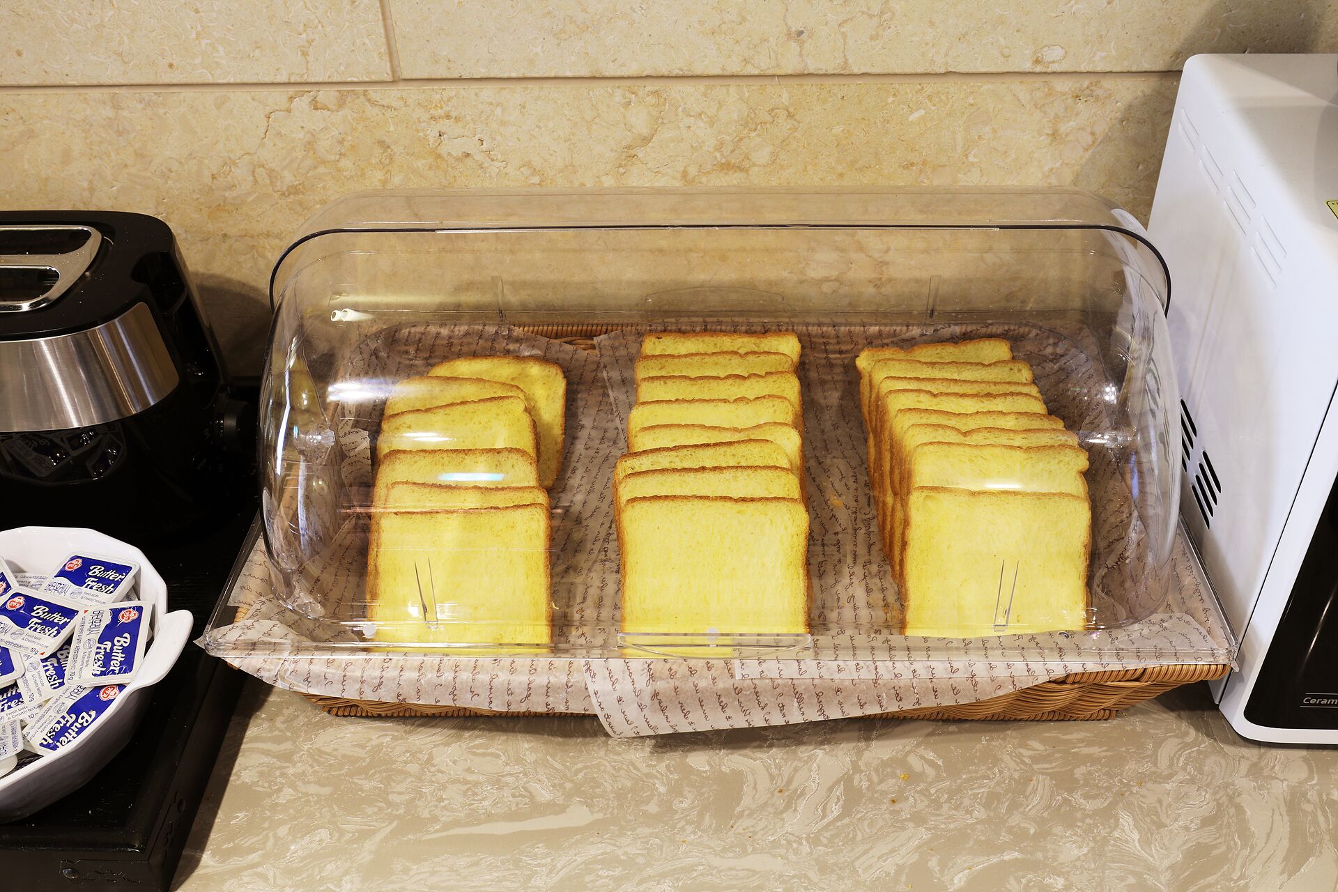 A glass baking dish with slices of bread on a kitchen counter.