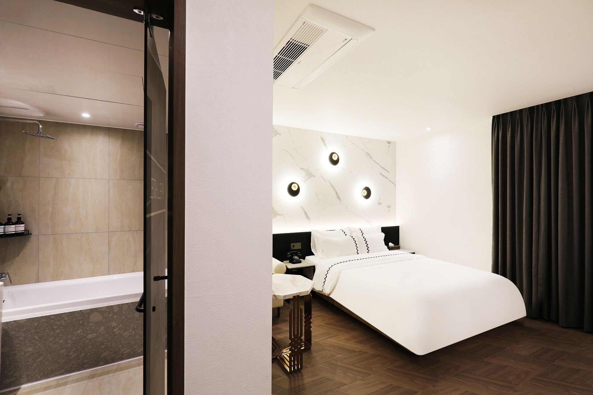 Una habitación de hotel moderna con una cama grande, un baño con bañera y ducha.