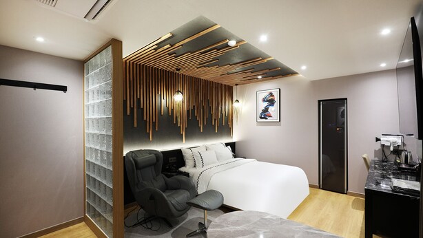 Une chambre moderne comprenant un lit, deux fauteuils, un bureau et une salle de bain.