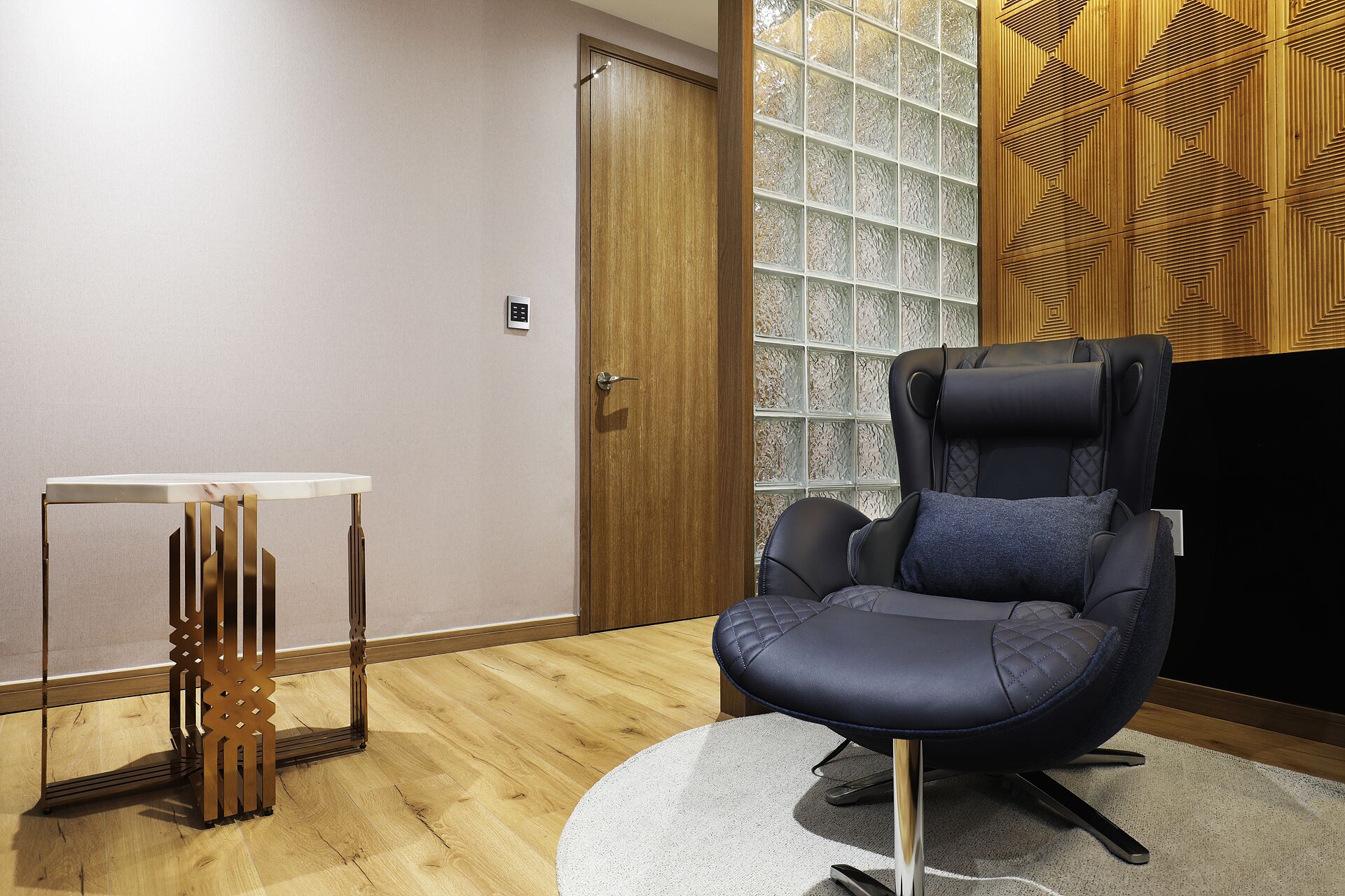 Ein modernes Zimmer mit Massagesessel, kleinem Tisch und Holzboden.