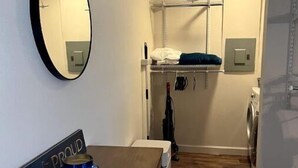 A compact room with a bunk bed, a washing machine, a mirror, and a small table with a candle. - Cuddly Critters Cottage - Alpacas, Goats, Emu's and YOU! (Blue Ridge)