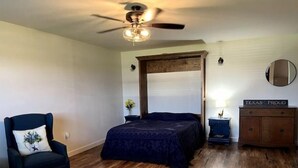 A bedroom with a bed, a chair, a dresser, a mirror, and a ceiling fan. - Cuddly Critters Cottage - Alpacas, Goats, Emu's and YOU! (Blue Ridge)