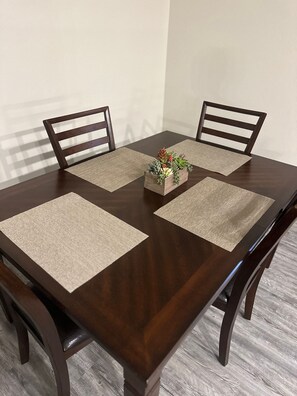 Une table à manger avec quatre chaises, une plante d’ornement au centre et des sets de table.