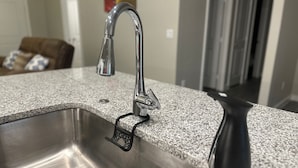 Un lavamanos de cocina con un grifo moderno y un dispensador de jabón negro.
