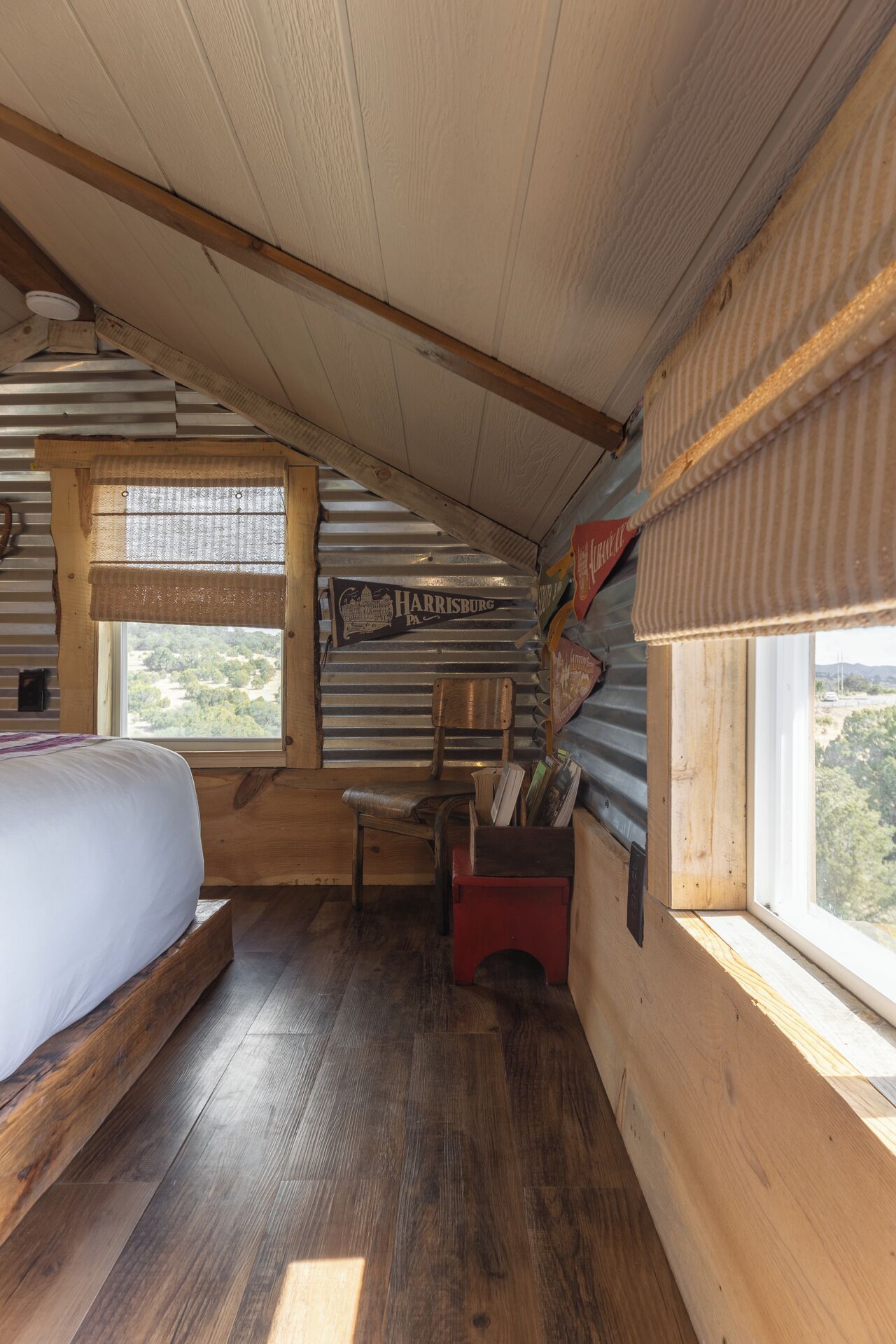 Une chambre confortable dans un chalet, avec un lit en bois, une chaise, une petite table et une fenêtre donnant sur le paysage extérieur.