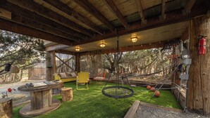 Une terrasse extérieure avec une table en bois, une chaise jaune, un hamac et un extincteur.