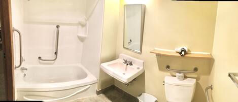 A bathroom with a bathtub, sink, toilet, and a mirror.