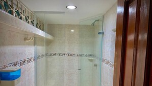 A modern bathroom with a glass shower enclosure, a toilet, and a sink with a blue basin.