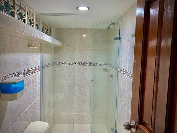 Un bagno moderno con cabina doccia in vetro, un water e un lavabo con lavandino blu.