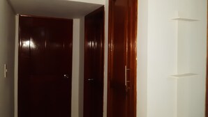 A hallway with two wooden doors, one closed and one partially open.