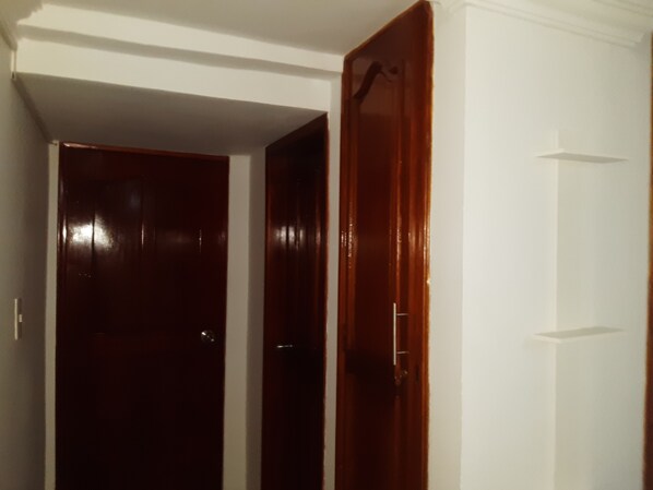 A hallway with two wooden doors, one closed and one partially open. - Habitacion Love, Hermosa Ubicada Cerca de Restaurantes Tipicos (Barranquilla)