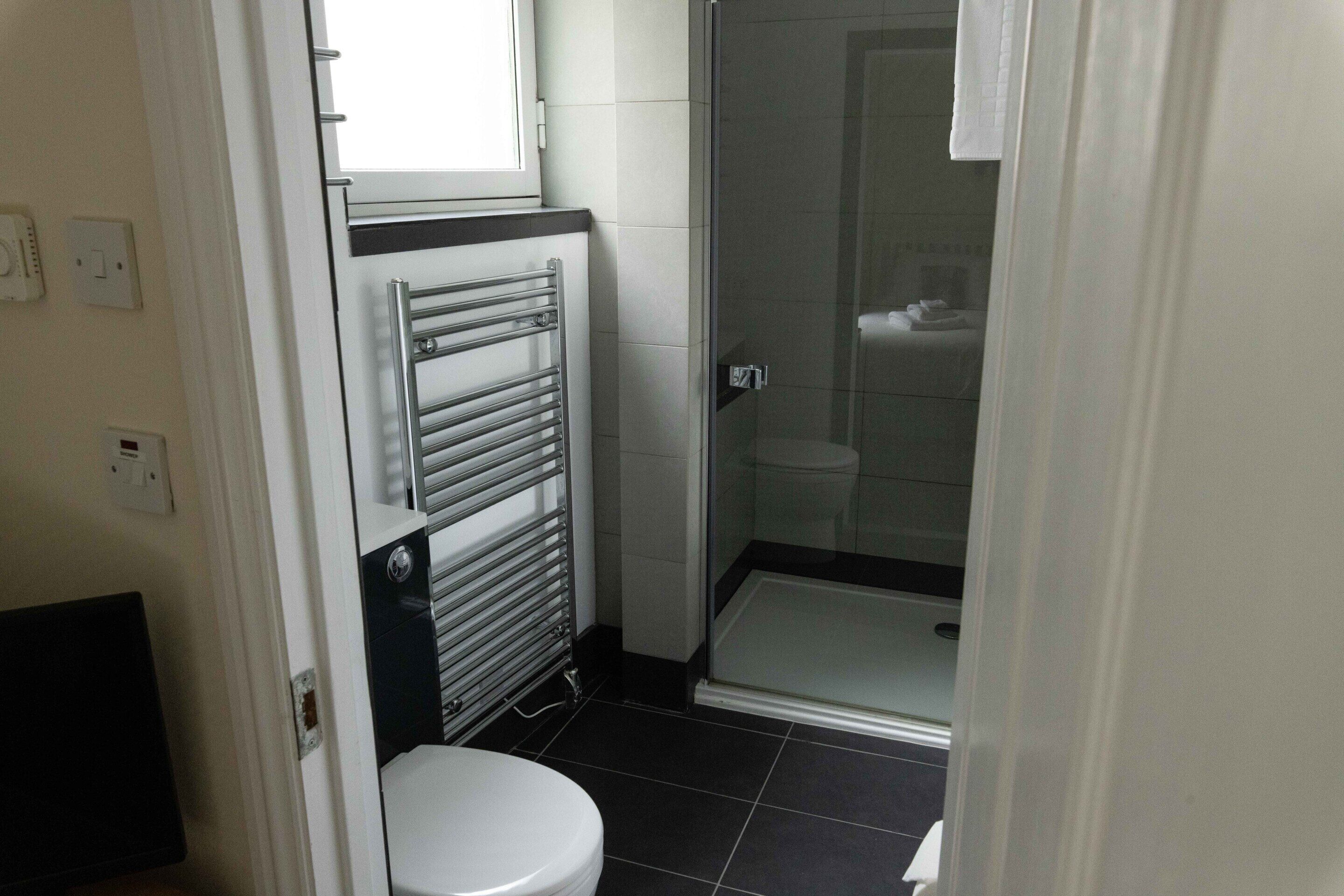 A bathroom with a toilet, a glass shower enclosure, and a towel rack.