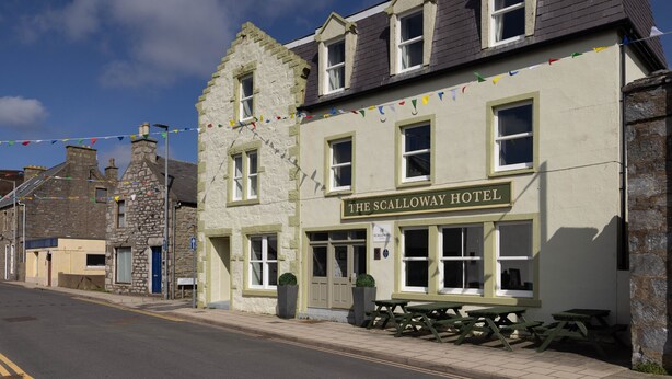 Hotel Scalloway con fachada de piedra tradicional, numerosas ventanas y un cartel.