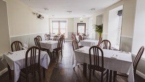 Un comedor con varias mesas y sillas, un extintor y una planta en maceta.