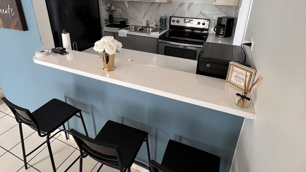 A compact kitchen with a bar area, featuring a refrigerator, stove, microwave, and a coffee maker. - Cozy in Cabo offers a beautiful stay in Cabo Rojo Puerto Rico 10m from beach.  (Cabo Rojo)