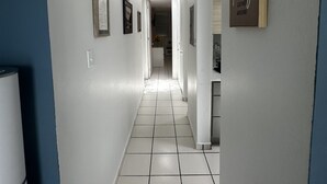 A hallway with white tiled flooring, a refrigerator on the left, and a framed quote on the right wall. - Cozy in Cabo offers a beautiful stay in Cabo Rojo Puerto Rico 10m from beach.  (Cabo Rojo)
