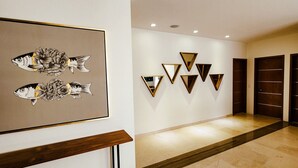 A hallway with a framed artwork of fish and flowers, a series of triangular mirrors, and dark wooden doors. - Ocean-View Rooftop Oasis- Pool, Hot Tub, Fire Pits, 5 minutes to beach & DT Cabo (El Tezal)