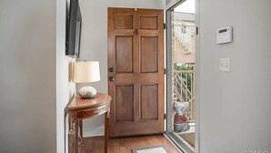 Une porte en bois avec un panneau de verre, une petite table avec une lampe et un thermostat fixé au mur.
