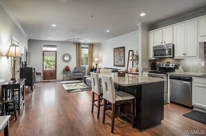 Una cocina amplia con una isla central, armarios blancos y electrodomésticos modernos.