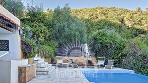Un espace piscine aménagé avec des chaises longues, une table et une pergola.