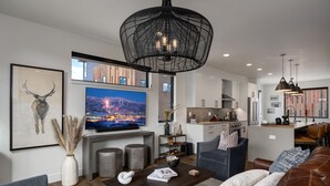 A modern living room with a large flat-screen TV, a dark wood coffee table, and a leather sofa. - Luxury Townhouse with Rooftop Deck & Hot Tub, Close to Skiing - Skyline Retreat (Steamboat Springs)