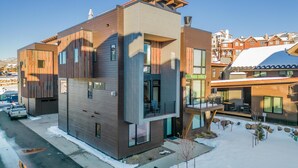 A modern multi-story building with a flat roof, large windows, and a balcony. - Luxury Townhouse with Rooftop Deck & Hot Tub, Close to Skiing - Skyline Retreat (Steamboat Springs)
