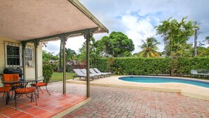 A covered patio with a pool, lounge chairs, and a grill area. - Amazing pool and nearby beach - Bliss (Sunset Crest)