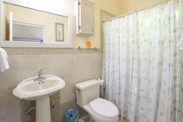 Un baño con lavamanos, inodoro y cortina de ducha.