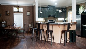 A kitchen with dark green cabinets, a stainless steel refrigerator, a wooden island with bar stools, and pendant lighting. - Spring Warrior Pines
5 min to the ocean, boat ramp, and the WMA. (Perry)