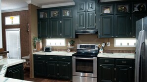 A kitchen with dark green cabinets, a stainless steel oven, and a microwave. - Spring Warrior Pines
5 min to the ocean, boat ramp, and the WMA. (Perry)