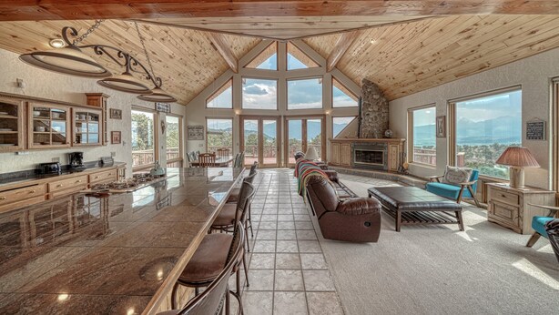 A spacious kitchen with a large island, a dining area with a long table and chairs, a cozy seating area with a sofa and armchairs, and large windows offering a view of the mountains. - Mountain Views• Private Hot Tub•Large Deck (Salida)