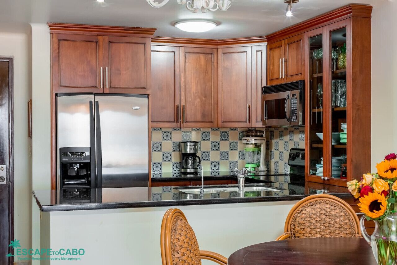 A kitchen with wooden cabinets, stainless steel appliances, and a tiled backsplash.