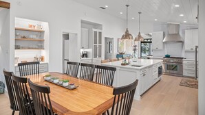 A modern kitchen with white cabinetry, a central island, and pendant lighting.
