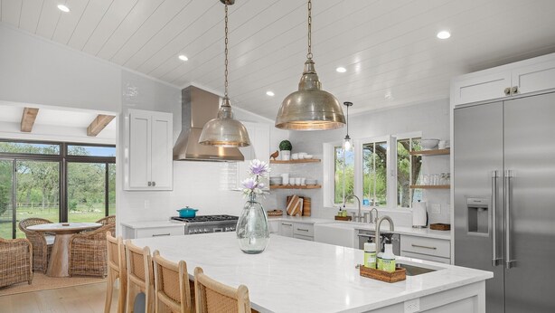 A modern kitchen with a large island, stainless steel appliances, and pendant lighting.