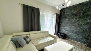 A modern living room with a beige sofa, a white coffee table, and a dark stone accent wall. - Holiday apartment with jacuzzi and sea view (Dramalj)