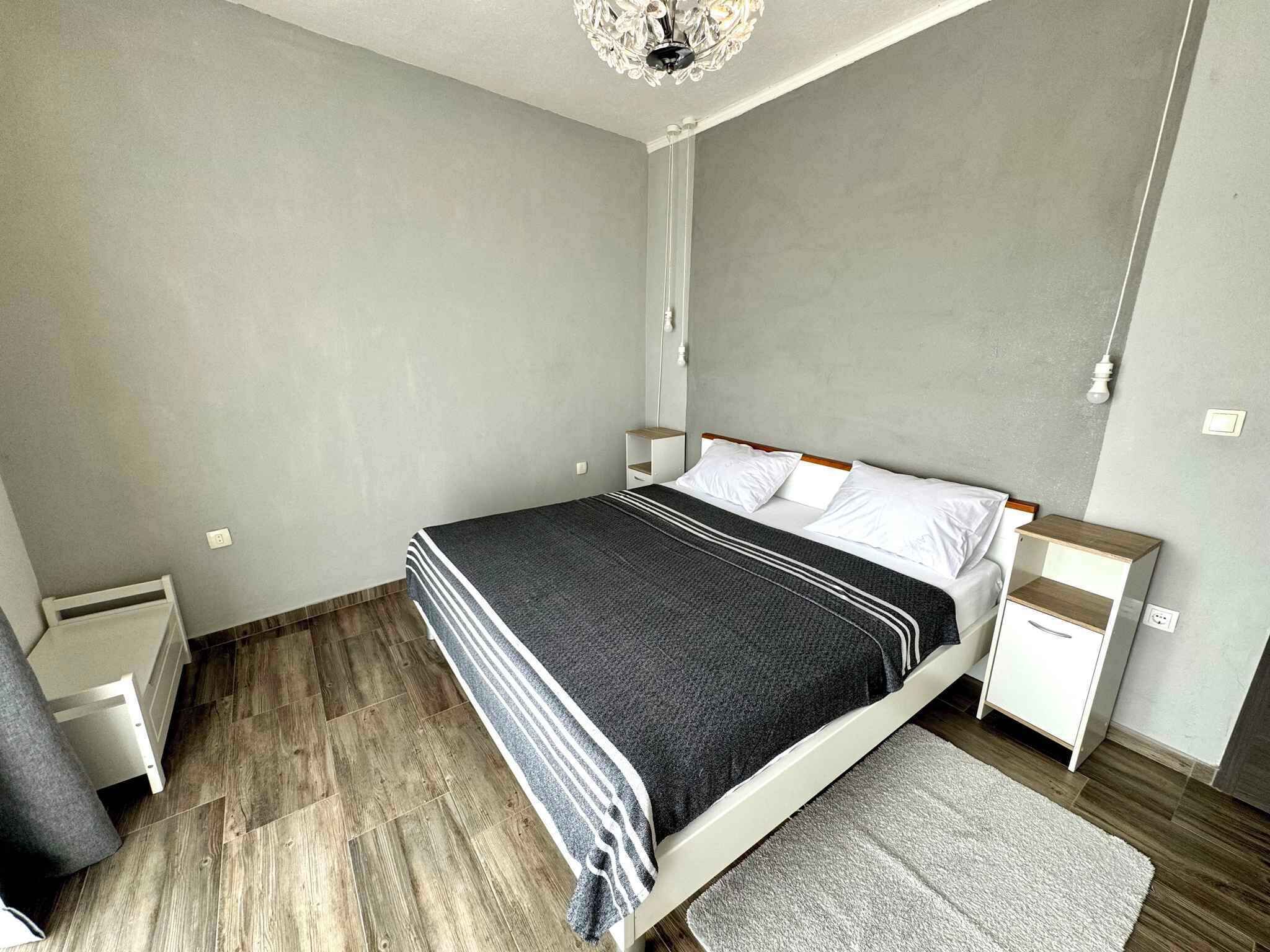 Une chambre à coucher comprenant un lit, des tables de chevet, une commode, un tapis et un lustre.