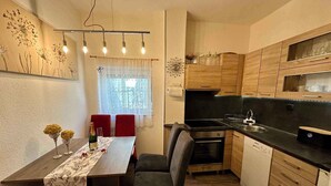 A compact kitchen with a dining area, wooden cabinets, a black countertop, and a dining table set for two. - Holiday apartment with jacuzzi and sea view (Dramalj)