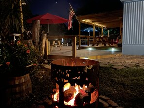 Un patio in legno con un braciere, un ombrellone rosso e una bandiera americana.