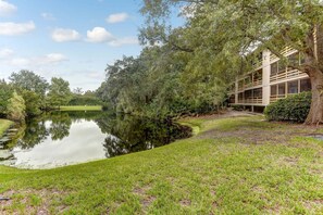 A tranquil lakeside setting with a building featuring a modern design, surrounded by lush greenery and trees.