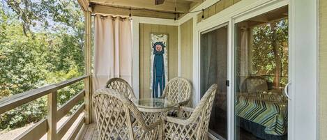 A covered porch with wicker chairs, a glass table, and a ceiling fan.