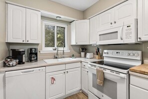 A modern kitchen with white cabinetry, a built-in microwave, a stove, and a coffee maker. - 2 blocks to the beach! Elegant Second floor 2 BR/2 BA - Secluded Lanai, WiFI, Pool & Tennis (Fernandina Beach)