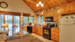 Una cocina con armarios de madera, microondas, refrigerador y un comedor con mesa y sillas.