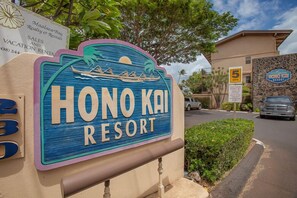 Señal del Honolulu Resort, con un diseño tropical, una palmera y un bote.