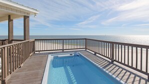 En træterrasse med pool, med udsigt over en strand.