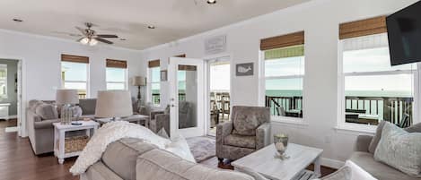 A spacious living room with a ceiling fan, a sofa, a coffee table, and a TV.