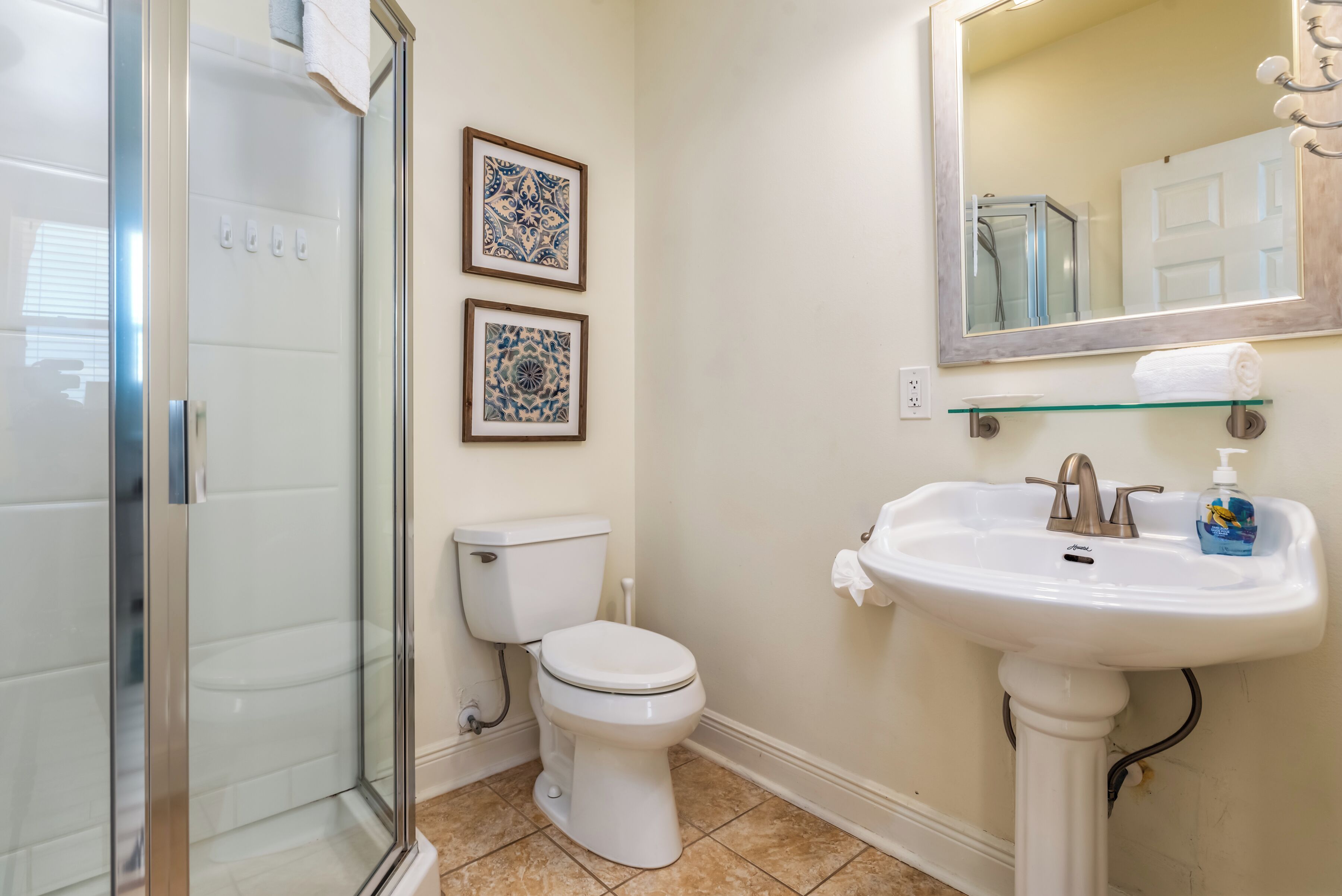 Une salle de bain avec une douche à parois de verre, des toilettes et un lavabo avec un miroir au-dessus.