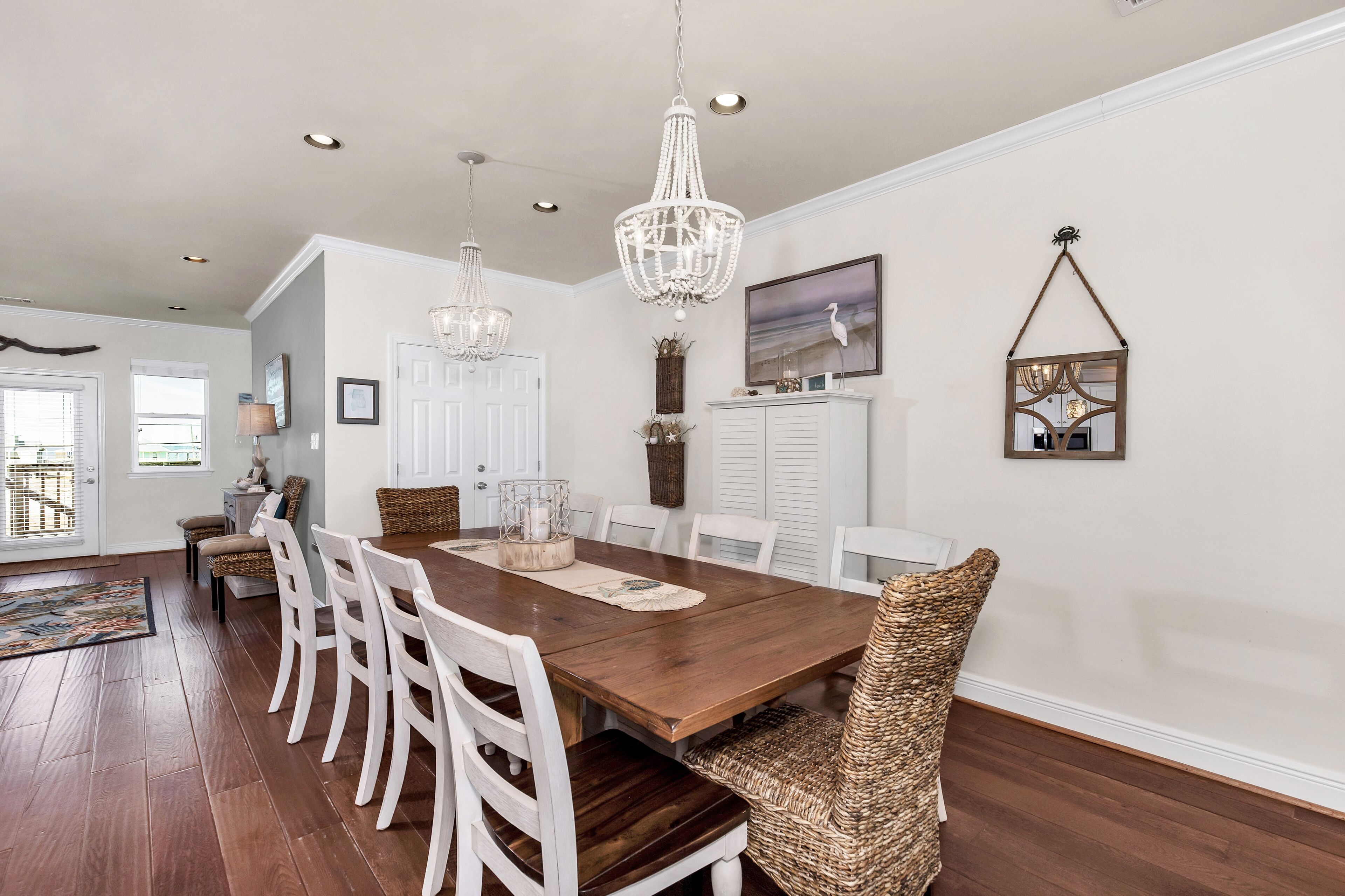 A dining room with a wooden table, white chairs, and a chandelier.
