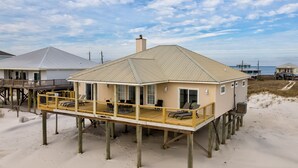 Ett hus vid stranden med en täckt veranda och utsikt över havet.