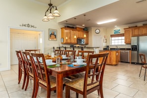 A spacious kitchen with wooden cabinets, a dining table set for six, and a refrigerator. - Thisldu | Peaceful Home on the Gulf of Mexico (Dauphin Island)